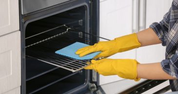 woman-cleaning-oven-in-kitchen-closeup-picture-id942141666